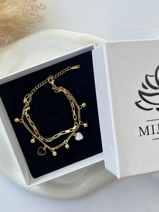 Reversible gold charm bracelet with black and white enamel heart pendants, layered chain design, and anti-tarnish finish — a trendy, versatile gift option for girls or women who love playful and elegant jewelry.