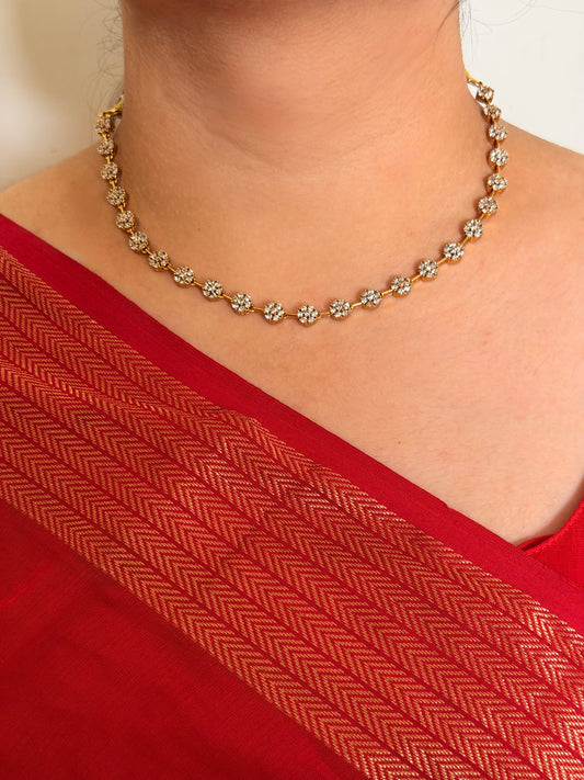 Necklace with floral design worn by a person in a red garment.