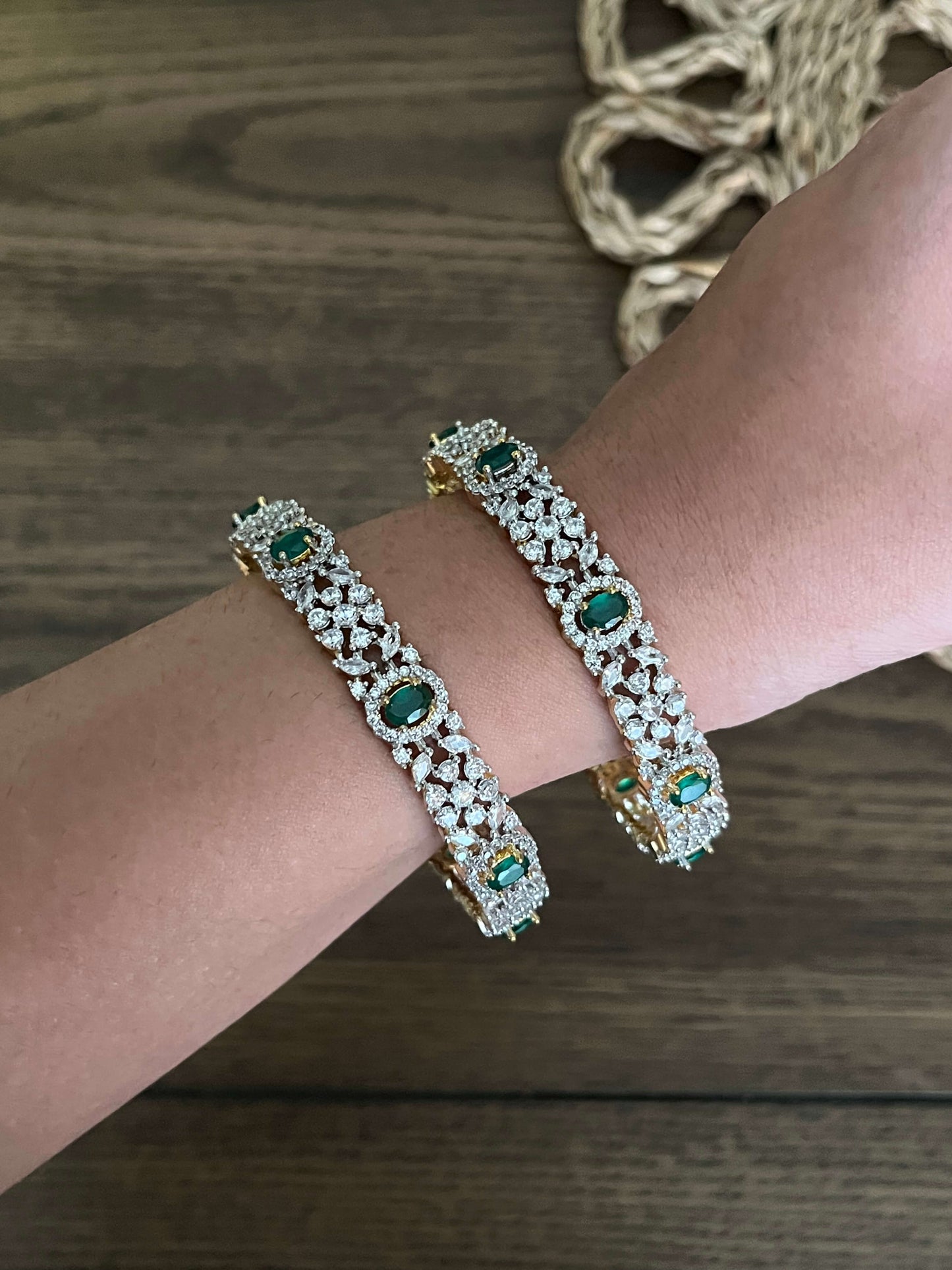 Pair of premium AD bangles with emerald green stones and gold finish – worn on wrist – traditional festive jewellery