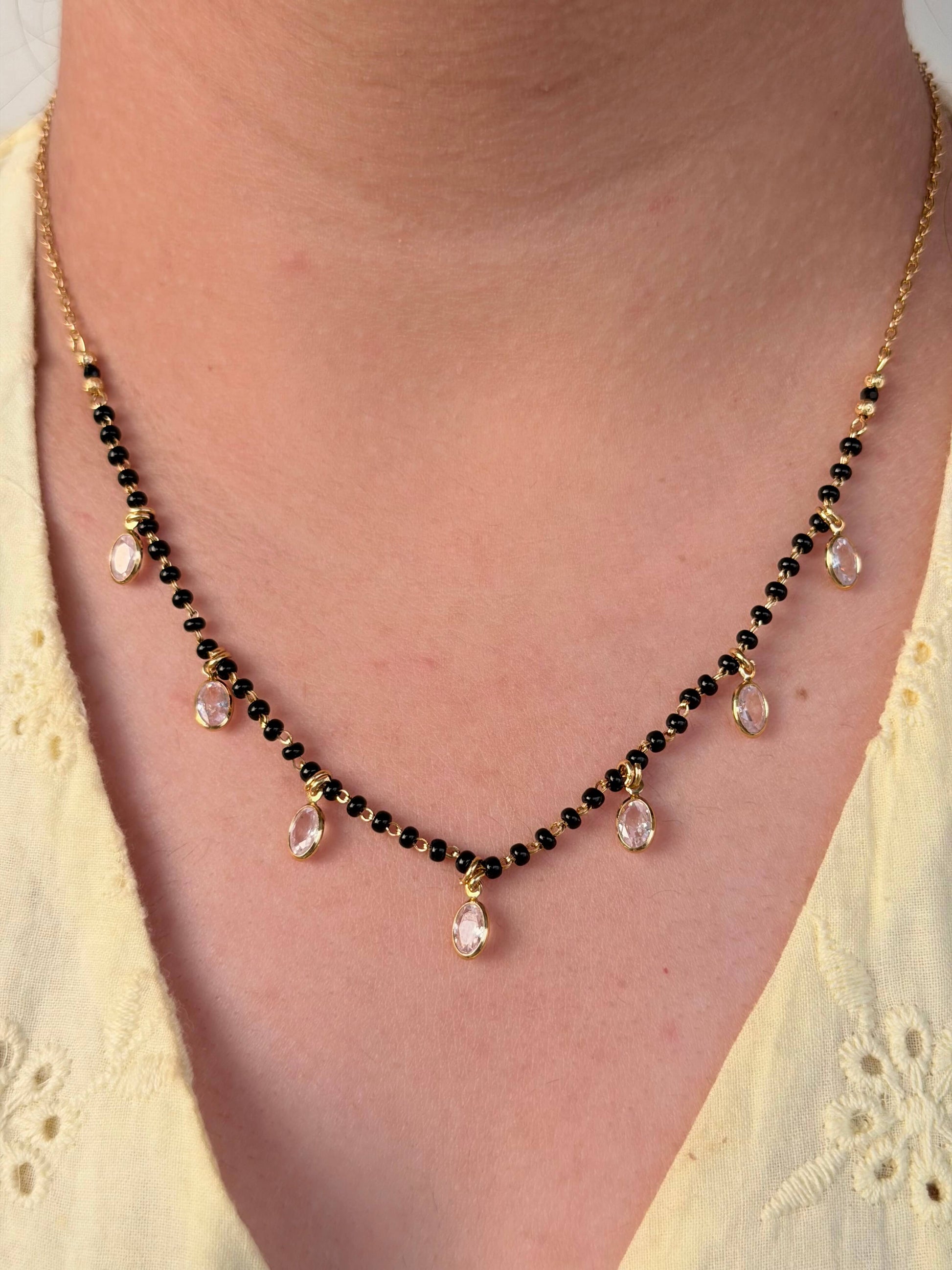 Necklace with black and pink beads worn by a person