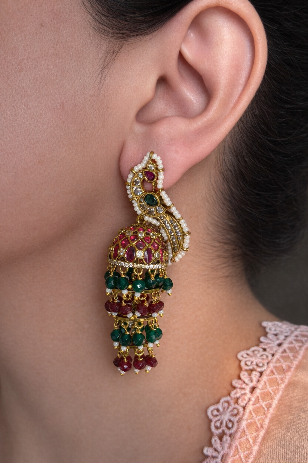 Close-up of an ear wearing a decorative earring with gemstones.