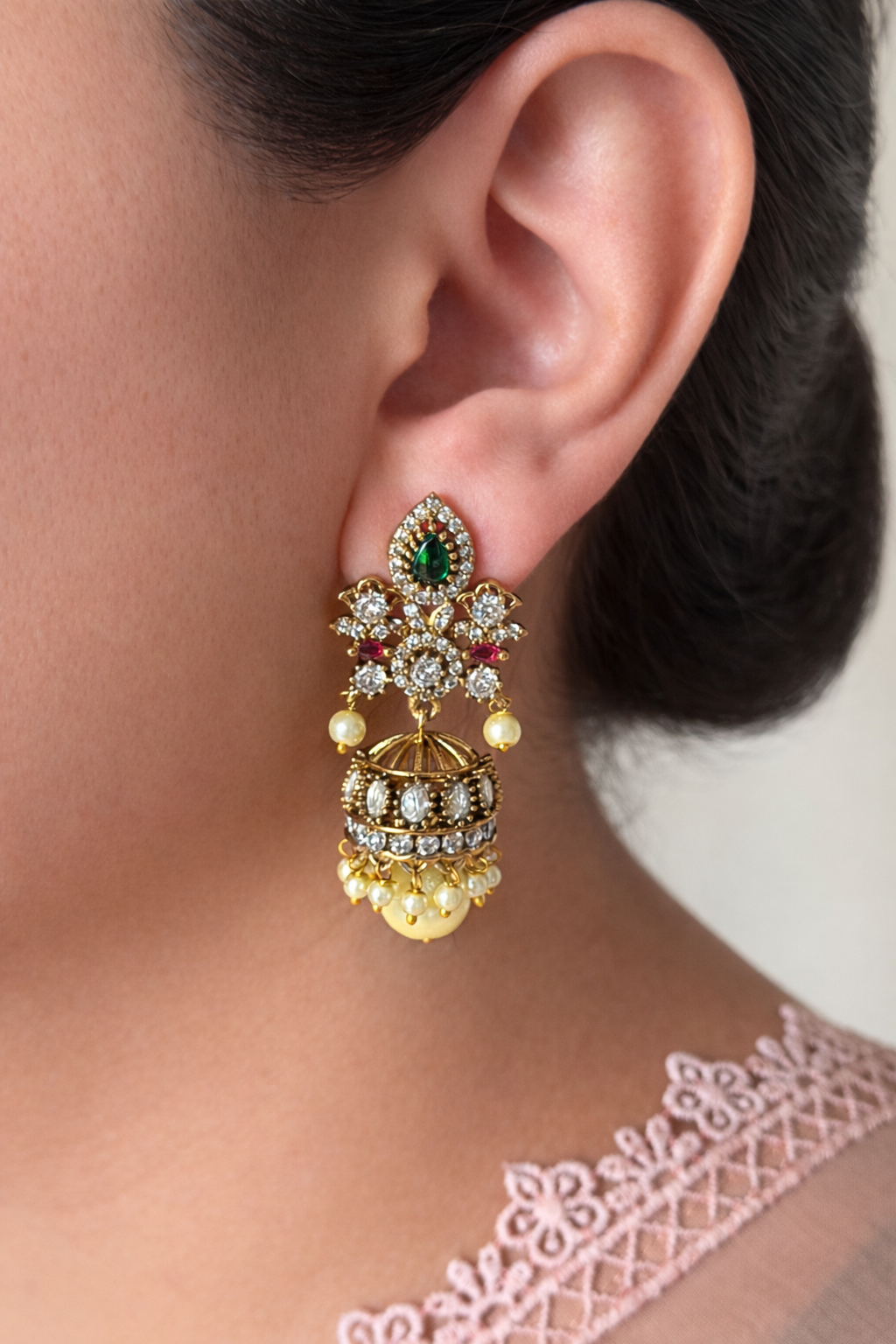 Close-up of a person wearing a decorative gold earring with gemstones.